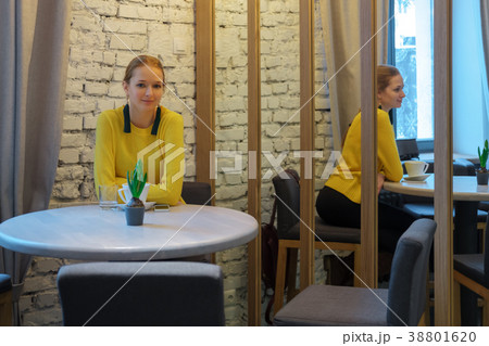 Pretty girl in cafe behind the table near mirror 38801620