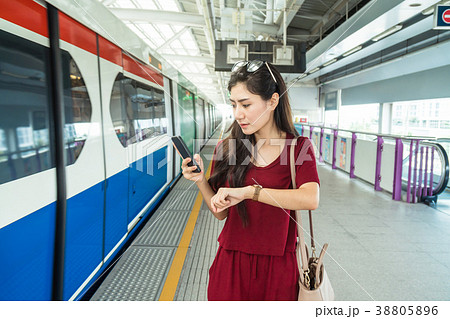 Asian woman passenger with casual suit watching the clock and waiting in the BTS Skytrain rails or MRT subway for travel in the big city, lifestyle and transportation concept 38805896
