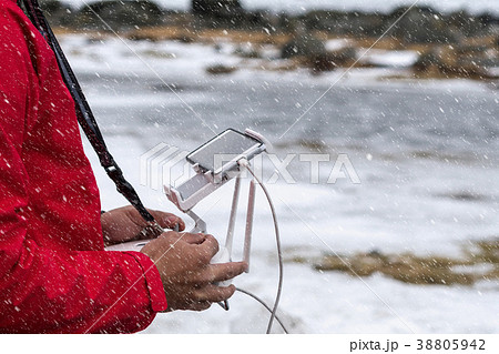 Closeup the photographer hand controling the drone over the Seascape with snow at the Uttakleiv beach in winter, Lototen, Norway photographer and transportation concept Closeup the photographer hand controling the drone over the Seascape with snow at the Uttakleiv beach in winter, Lototen, Norway photographer and transportation concept 38805942
