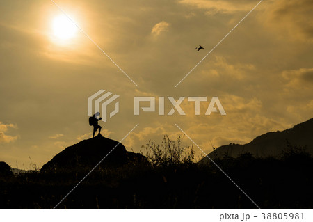 Silhouette of photographer with drone over the mountain, tphotographer and ransportation concept Silhouette of photographer with drone over the mountain, tphotographer and ransportation concept 38805981