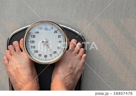 Close-up Feet Standing On Weighing Scale 38807476