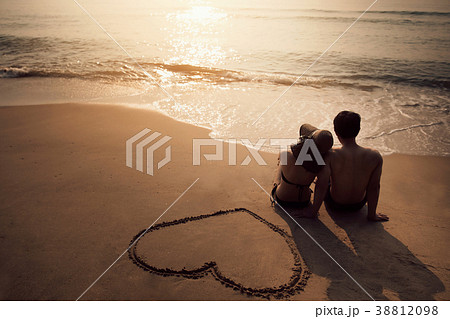 Couple sitting at the beach He was drawing a heart 38812098
