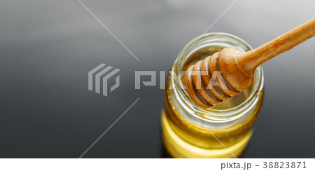 Honey jar with dipper and flowing honey Honey jar with dipper and flowing honey 38823871