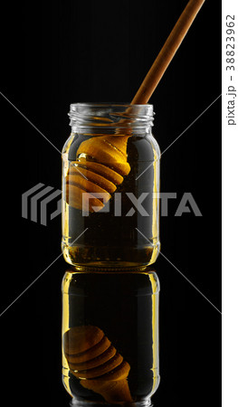Honey jar with dipper and flowing honey Honey jar with dipper and flowing honey 38823962