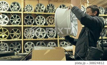 The man buys alloy wheels in his shop for his car. 38824812