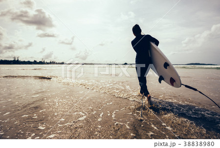 woman surfer with surfboard running on beach 38838980