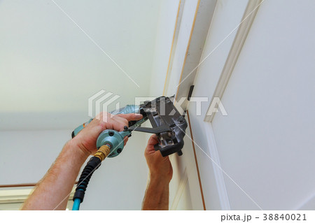 owner repairing door frame molding with nail gun, 38840021
