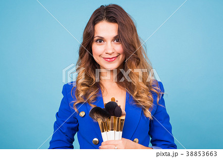 Young make-up artist with brushes on blue Young make-up artist with brushes on blue 38853663