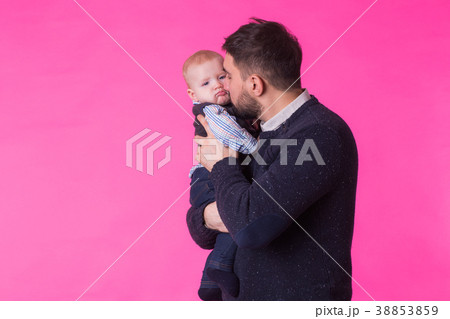 Happy father holding baby son in hands over pink Happy father holding baby son in hands over pink 38853859