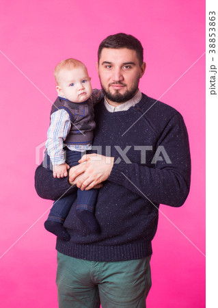 Happy father holding baby son in hands over pink Happy father holding baby son in hands over pink 38853863