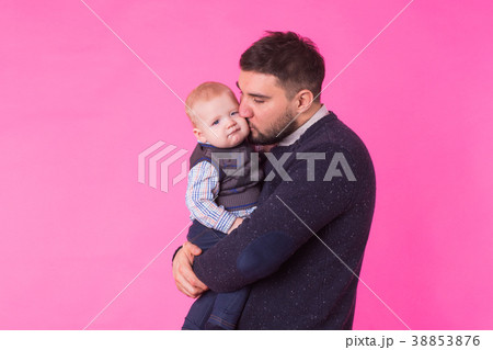 Happy father holding baby son in hands over pink Happy father holding baby son in hands over pink 38853876