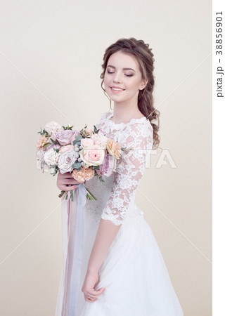 Attractive smiling woman holding a bouquet of flowers wearing in luxurious wedding dress Attractive smiling woman holding a bouquet of flowers wearing in luxurious wedding dress 38856901