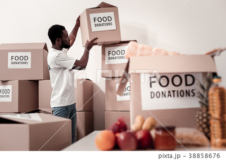 Serious volunteer collecting parcels with food Serious volunteer collecting parcels with food 38858676