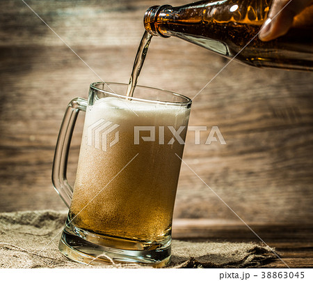 Beer from bottle filled into mug standing on 38863045
