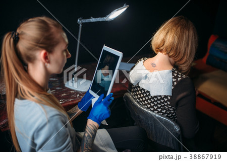 Tattooist makes shoot of tattoo on client back Tattooist makes shoot of tattoo on client back 38867919