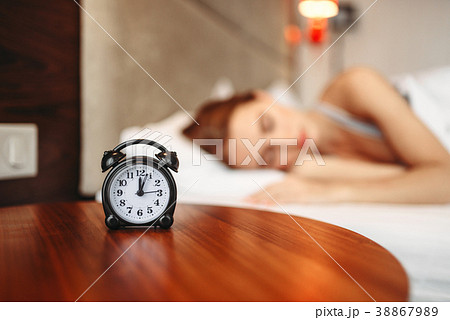 Alarm clock, woman covering her ears with pillow Alarm clock, woman covering her ears with pillow 38867989