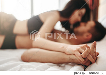 Sexy couple lying and kissing on big white bed Sexy couple lying and kissing on big white bed 38868157