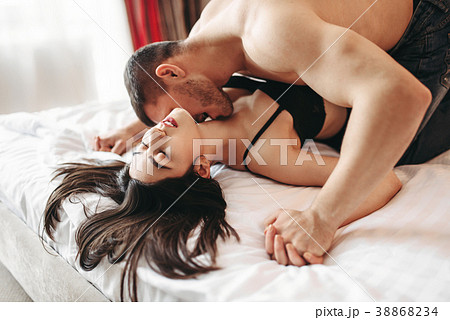 Sexy couple lying and kissing on big white bed 38868234