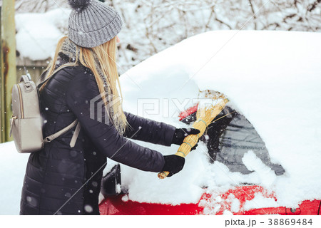 Winter portrait of a young woman cleaning snow  38869484