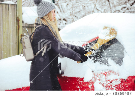Winter portrait of a young woman cleaning snow  38869487