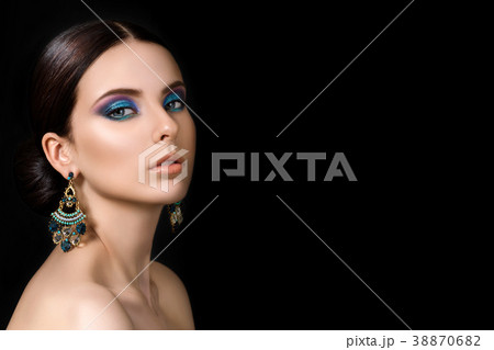 Portrait of beautiful brunet woman with blue earrings 38870682