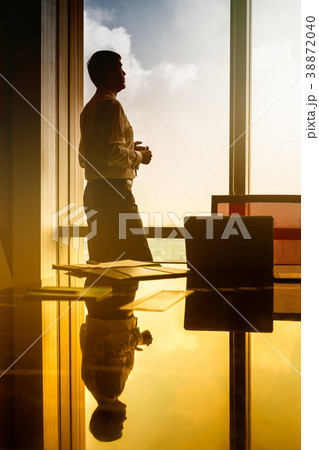 Business man standing on window looking at city Business man standing on window looking at city 38872040