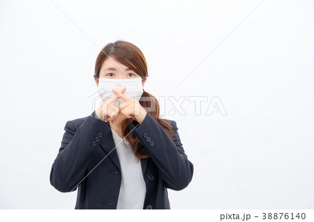 マスクの前で指を交差するスーツ姿の女性の写真素材