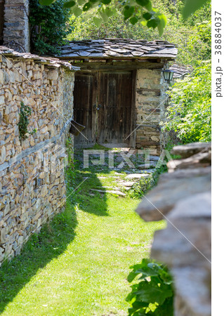 Narrow street with grass between old stone walls 38884037