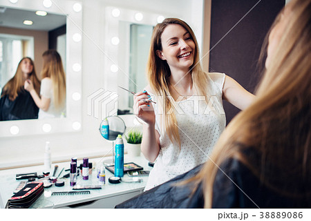 Cheerful young makeup artist working with a Cheerful young makeup artist working with a 38889086