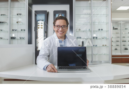 Cheerful ophthalmologist showing notebook computer 38889854