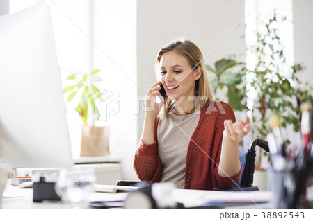 Businesswoman in wheelchair at the desk in her Businesswoman in wheelchair at the desk in her 38892543