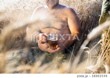 large glass of light beer is held by a fat man large glass of light beer is held by a fat man 38903549