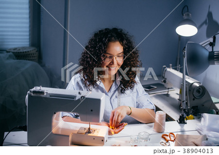 smiling seamstress sitting and holding beads in 38904013