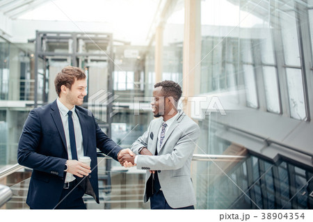 two multiracial businessmen handshaking in modern two multiracial businessmen handshaking in modern 38904354