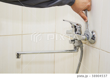 Plumber hands fixing water tap with spanner 38904537