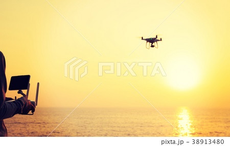 flying drone which taking photo over sunrise sea 38913480