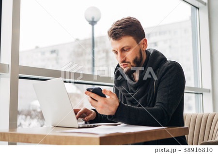 bearded hipster working at a laptop in a cafe 38916810