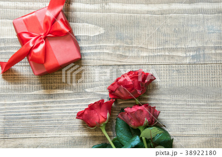 Bouquet red roses with gift on wooden table.  38922180