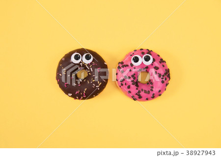 Colorful glazed donuts with funny eyes on yellow Colorful glazed donuts with funny eyes on yellow 38927943