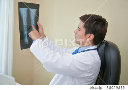 Smiling doctor posing in the office, he is wearing a stethoscope Smiling doctor posing in the office, he is wearing a stethoscope 38929836