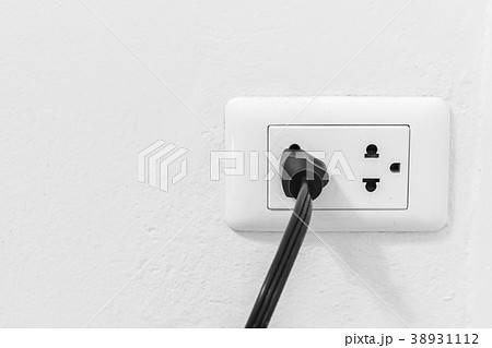 Black cable plugged in a white electric outlet  38931112