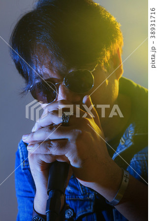 A man singing into a microphone under spotlight A man singing into a microphone under spotlight 38931716