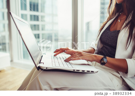 Side view of woman holding laptop on her lap Side view of woman holding laptop on her lap 38932334