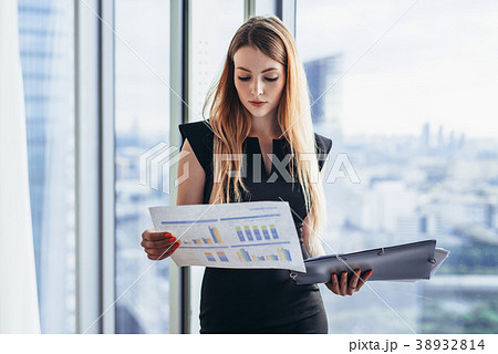 Female financial analyst holding papers studying Female financial analyst holding papers studying 38932814