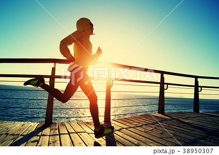sporty runner running on seaside boardwalk sporty runner running on seaside boardwalk 38950307