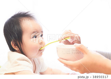 お母さんの手から離乳食のご飯を食べる赤ちゃんのアップ お母さんの手から離乳食のご飯を食べる赤ちゃんのアップ 38950317