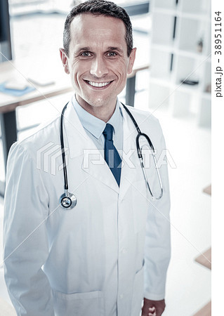 Responsible handsome doctor standing and smiling. Responsible handsome doctor standing and smiling. 38951164