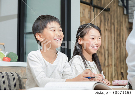 家族 父親 お父さん 姉弟 勉強 ダイニングキッチン ライフスタイル 宿題する小学生の写真素材