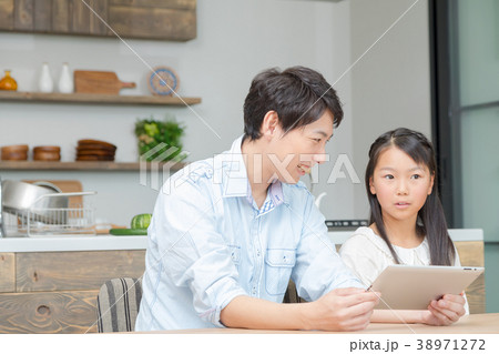 タブレット端末を操作する親子　父と娘　タブレットを見る親子　父親　お父さん　娘　女の子　生活感 38971272