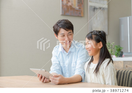 タブレット端末を操作する親子　父と娘　タブレットを見る親子　父親　お父さん　娘　女の子　生活感 38971274